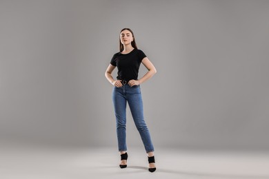 Photo of Beautiful young woman in stylish jeans on grey background