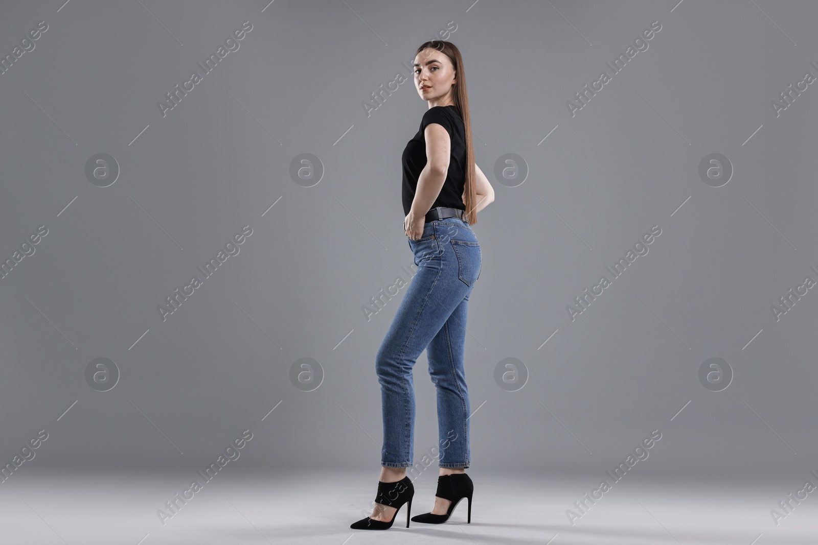 Photo of Woman in stylish jeans on grey background, low angle view