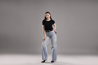 Photo of Beautiful young woman in stylish jeans on grey background