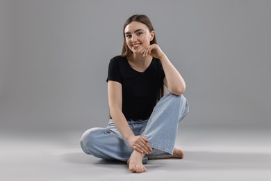 Photo of Smiling woman in stylish jeans on grey background