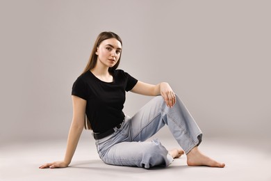 Photo of Beautiful young woman in stylish jeans on grey background