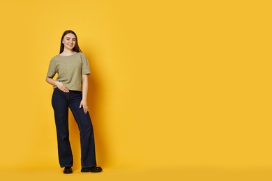 Photo of Smiling woman in stylish jeans on orange background. Space for text