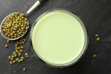 Photo of Fresh mung bean juice in glass and seeds on black table, flat lay
