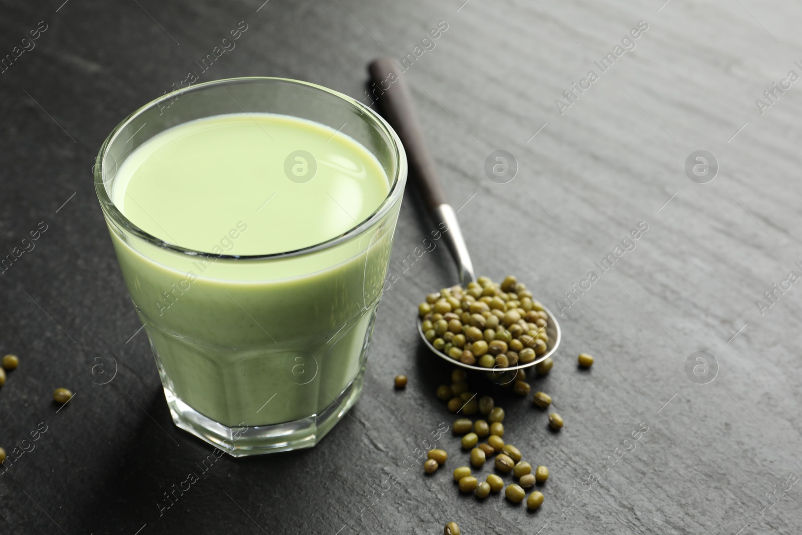 Fresh mung bean juice in glass and seeds on black table, closeup. Space for text Photo of Fresh mung bean juice in glass and seeds on black table, closeup. Space for text