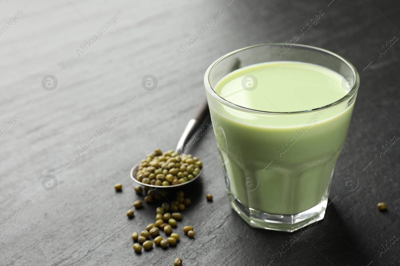 Fresh mung bean juice in glass and seeds on black table, closeup. Space for text Photo of Fresh mung bean juice in glass and seeds on black table, closeup. Space for text