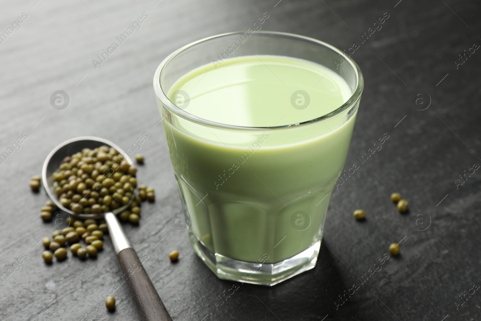 Fresh mung bean juice in glass and seeds on black table, closeup Photo of Fresh mung bean juice in glass and seeds on black table, closeup