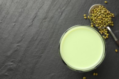 Photo of Fresh mung bean juice in glass and seeds on black table, flat lay. Space for text