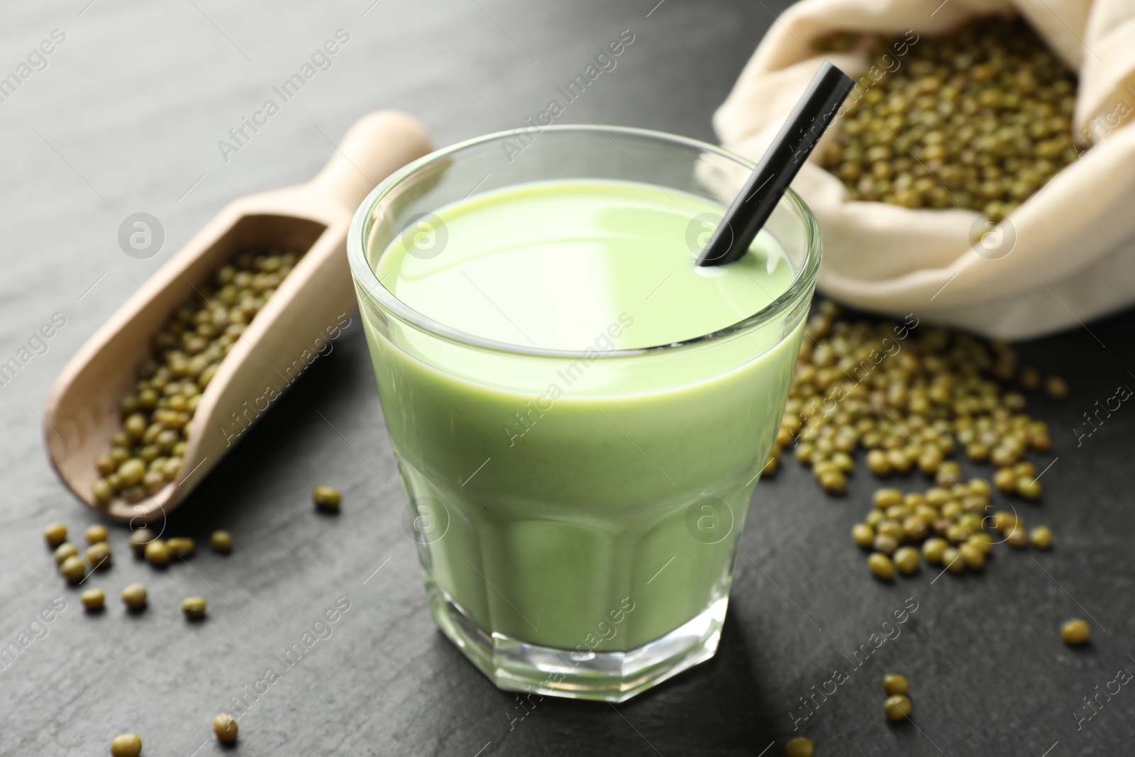 Fresh mung bean juice in glass, seeds and scoop on black table, closeup Photo of Fresh mung bean juice in glass, seeds and scoop on black table, closeup