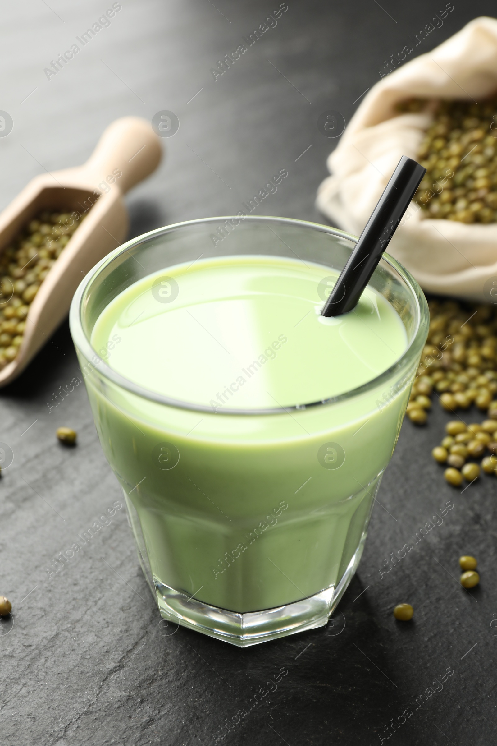 Fresh mung bean juice in glass, seeds and scoop on black table, closeup Photo of Fresh mung bean juice in glass, seeds and scoop on black table, closeup