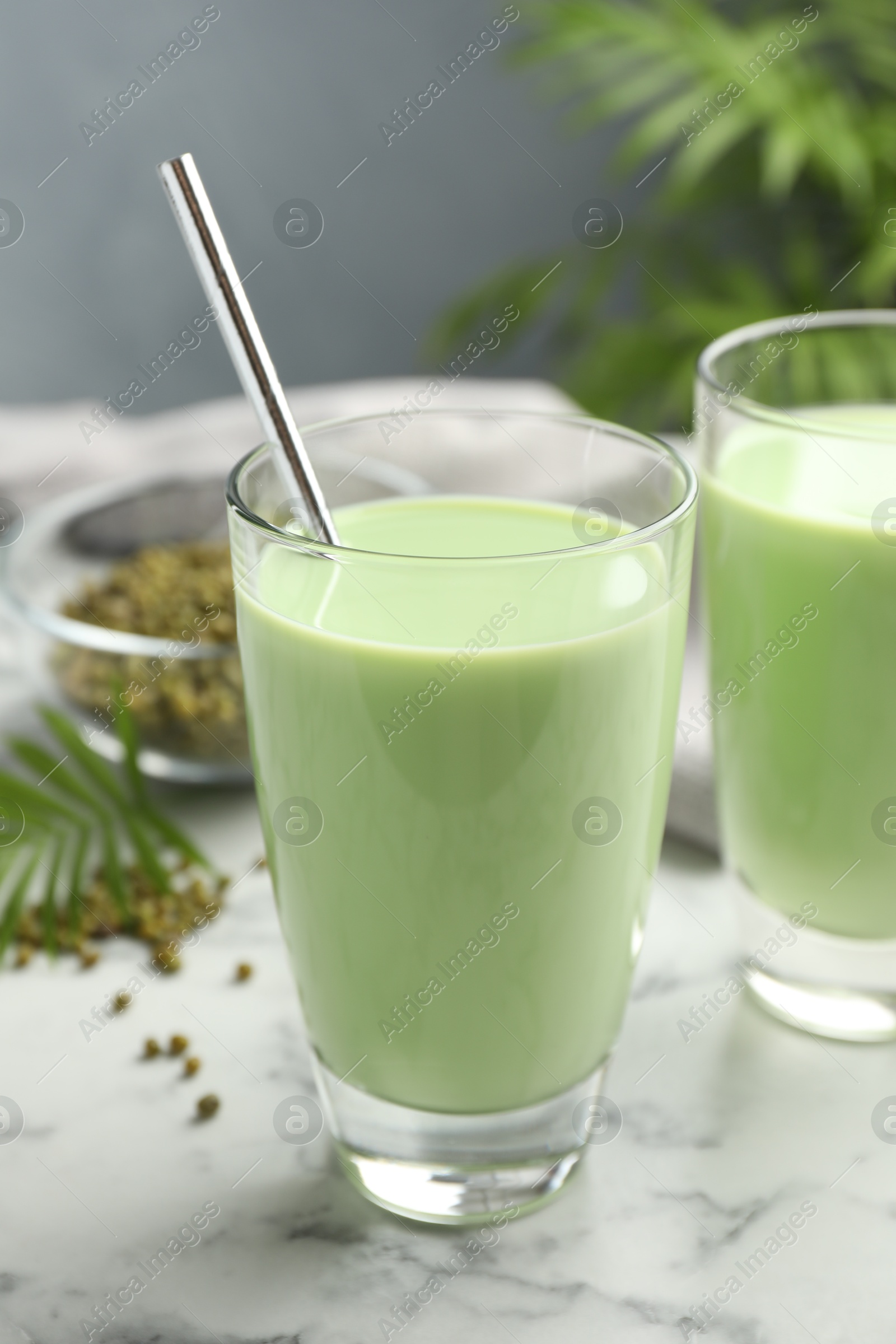 Fresh mung bean juice in glasses and seeds on white marble table, closeup Photo of Fresh mung bean juice in glasses and seeds on white marble table, closeup