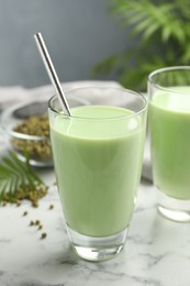 Photo of Fresh mung bean juice in glasses and seeds on white marble table, closeup