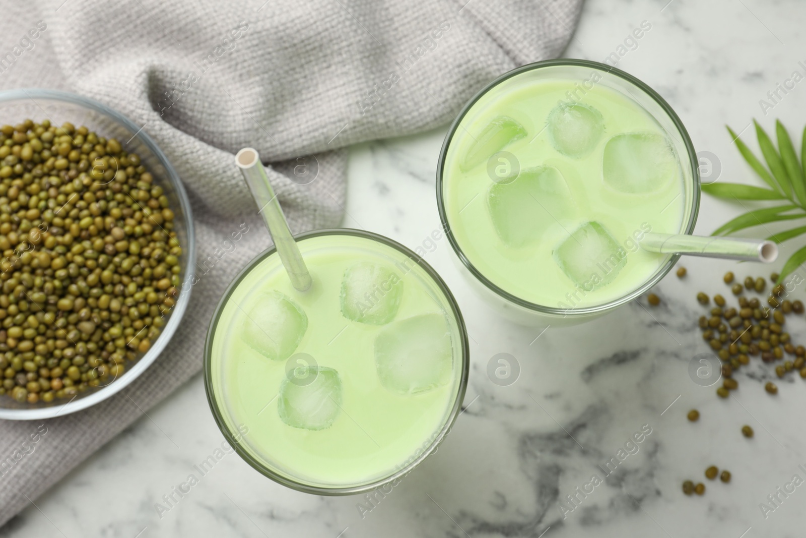 Fresh mung bean juice in glasses, seeds and green twig on white marble table, flat lay Photo of Fresh mung bean juice in glasses, seeds and green twig on white marble table, flat lay