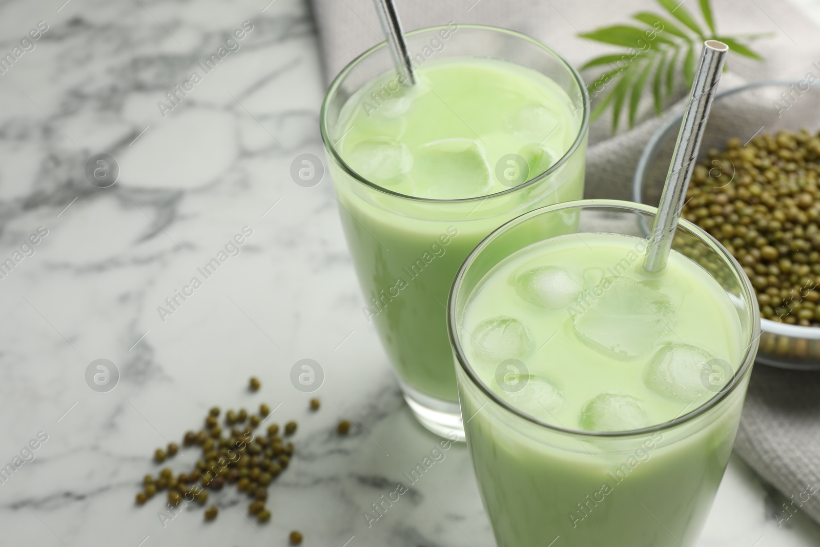 Fresh mung bean juice in glasses, seeds and twig on white marble table, closeup. Space for text Photo of Fresh mung bean juice in glasses, seeds and twig on white marble table, closeup. Space for text