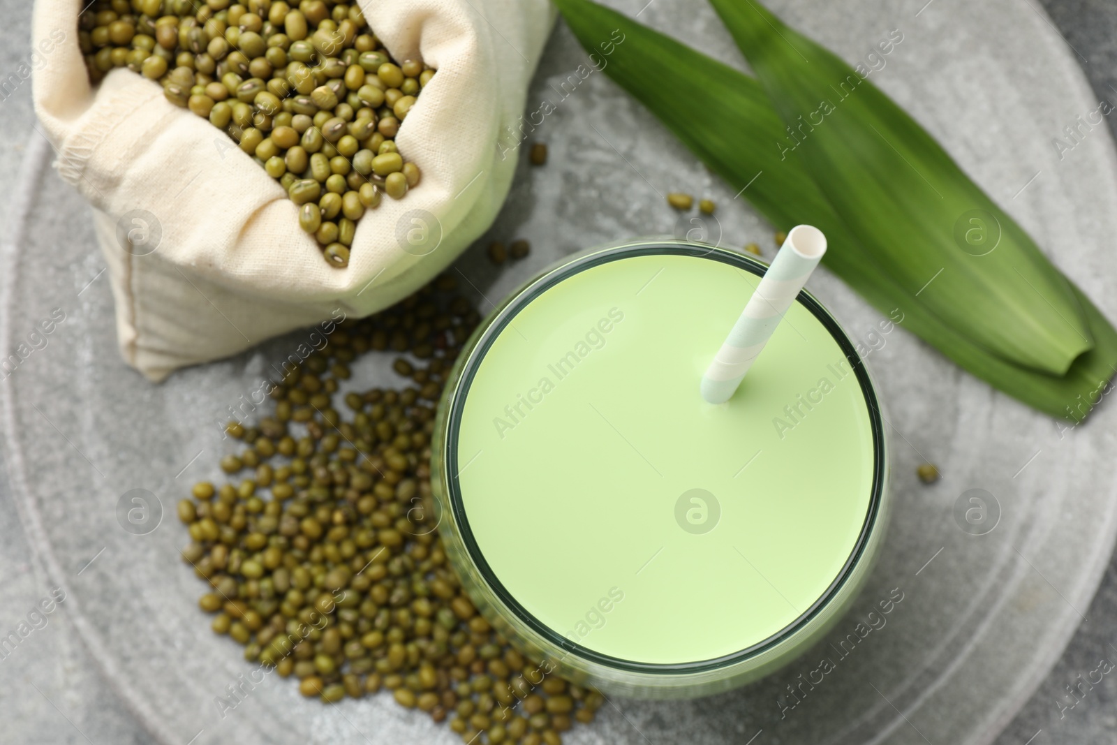 Fresh mung bean juice in glass, seeds and green leaves on table, top view Photo of Fresh mung bean juice in glass, seeds and green leaves on table, top view