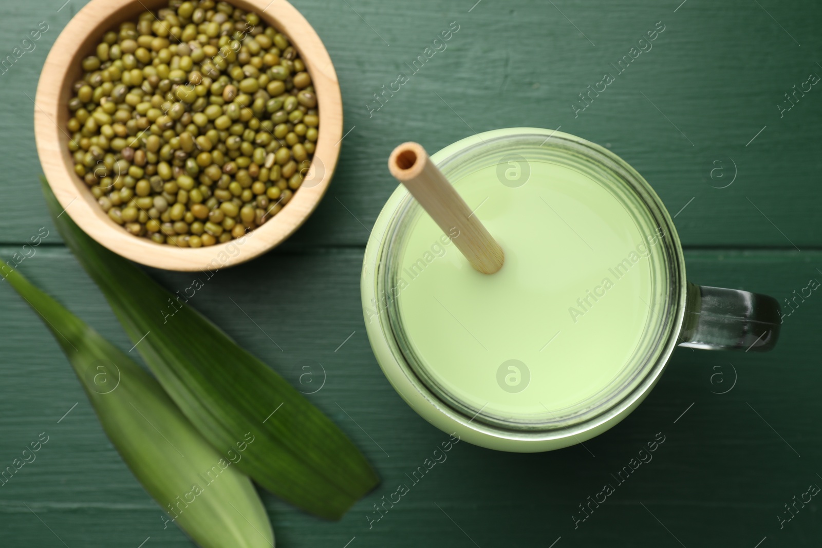 Fresh mung bean juice in mason jar, seeds and leaves on green wooden table, flat lay Photo of Fresh mung bean juice in mason jar, seeds and leaves on green wooden table, flat lay