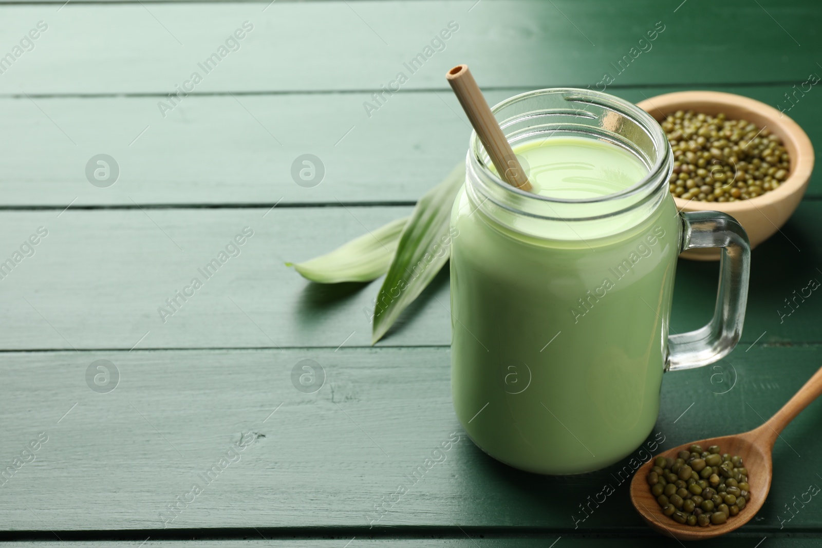 Fresh mung bean juice in mason jar, seeds and leaves on green wooden table, closeup. Space for text Photo of Fresh mung bean juice in mason jar, seeds and leaves on green wooden table, closeup. Space for text