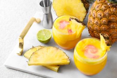 Photo of Tasty pineapple cocktail in glasses served on white table