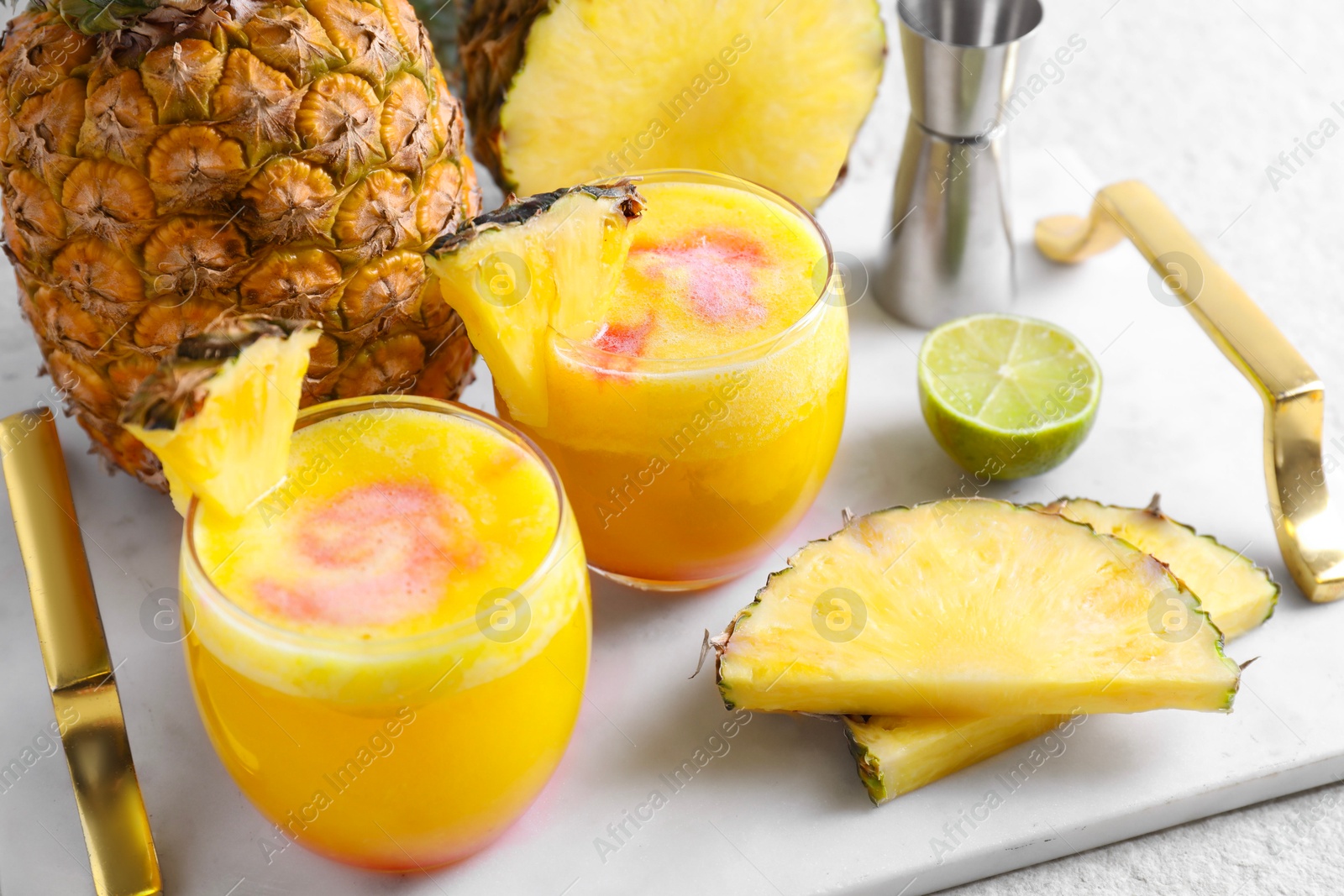 Photo of Tasty pineapple cocktail in glasses served on white table