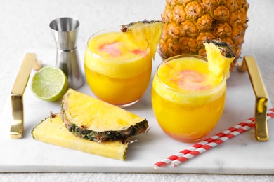 Photo of Tasty pineapple cocktail in glasses served on white table