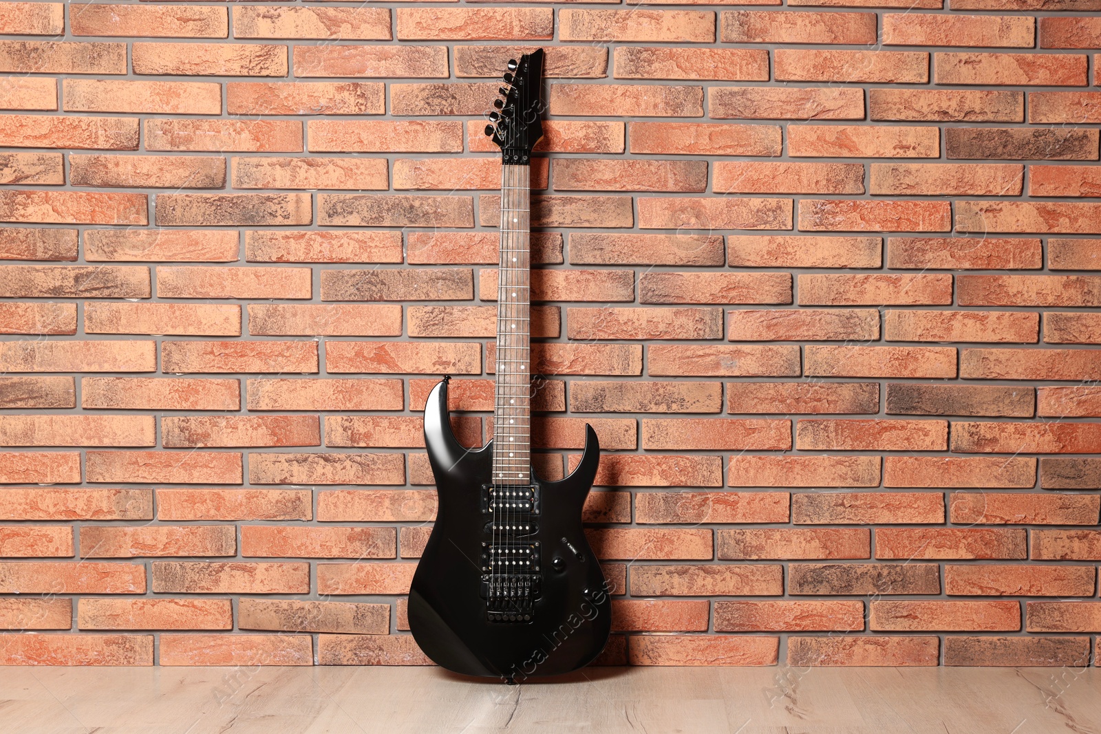 Photo of One modern electric guitar near brick wall