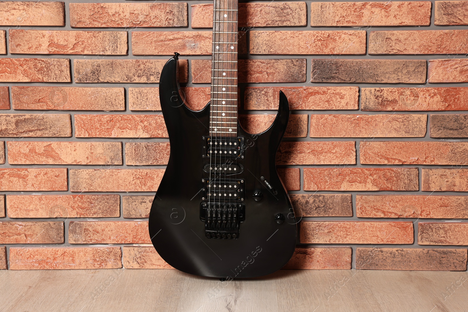 Photo of One modern electric guitar near brick wall