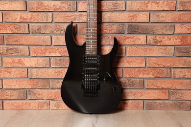 Photo of One modern electric guitar near brick wall