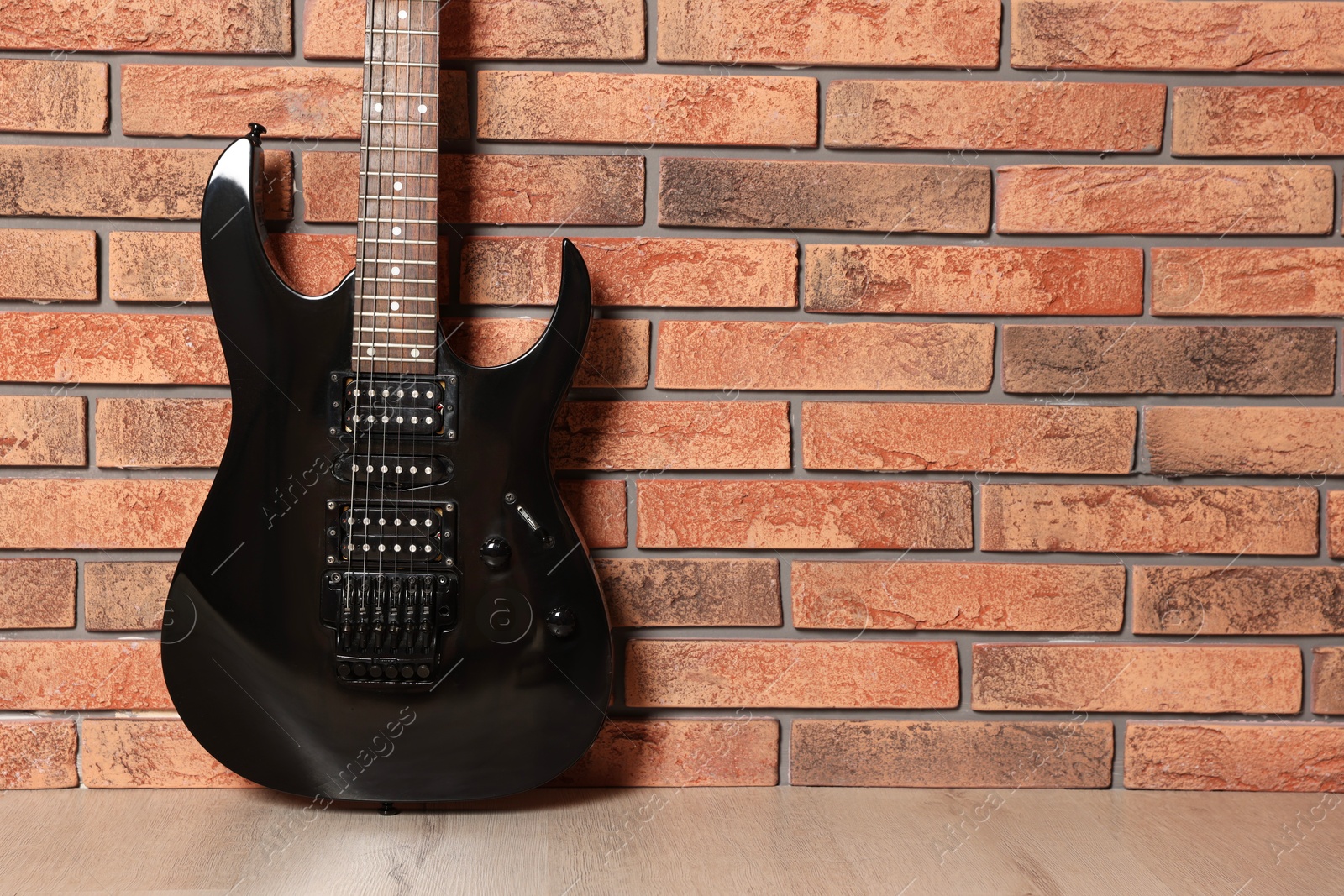 Photo of One modern electric guitar near brick wall. Space for text