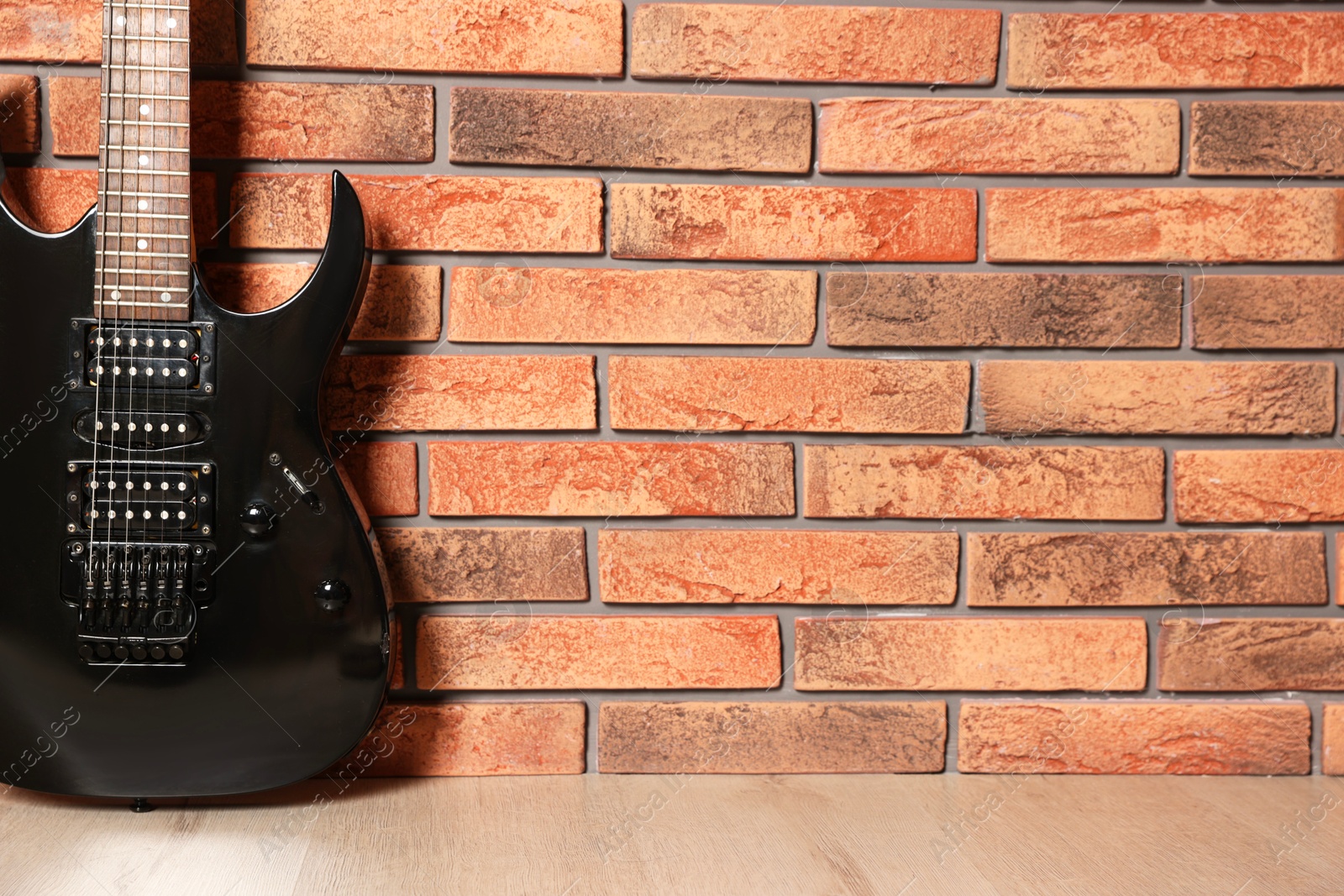 Photo of One modern electric guitar near brick wall. Space for text