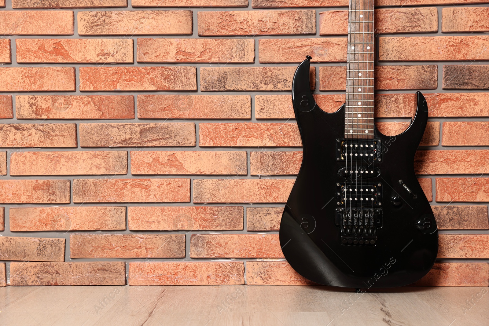 Photo of One modern electric guitar near brick wall. Space for text