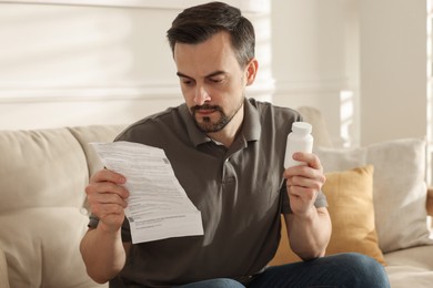 Man with pills reading instruction at home