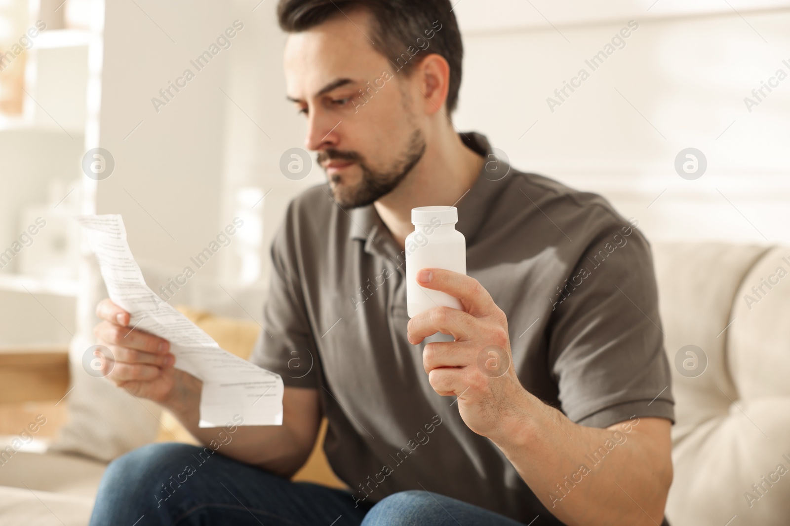 Photo of Man with pills reading instruction at home, selective focus