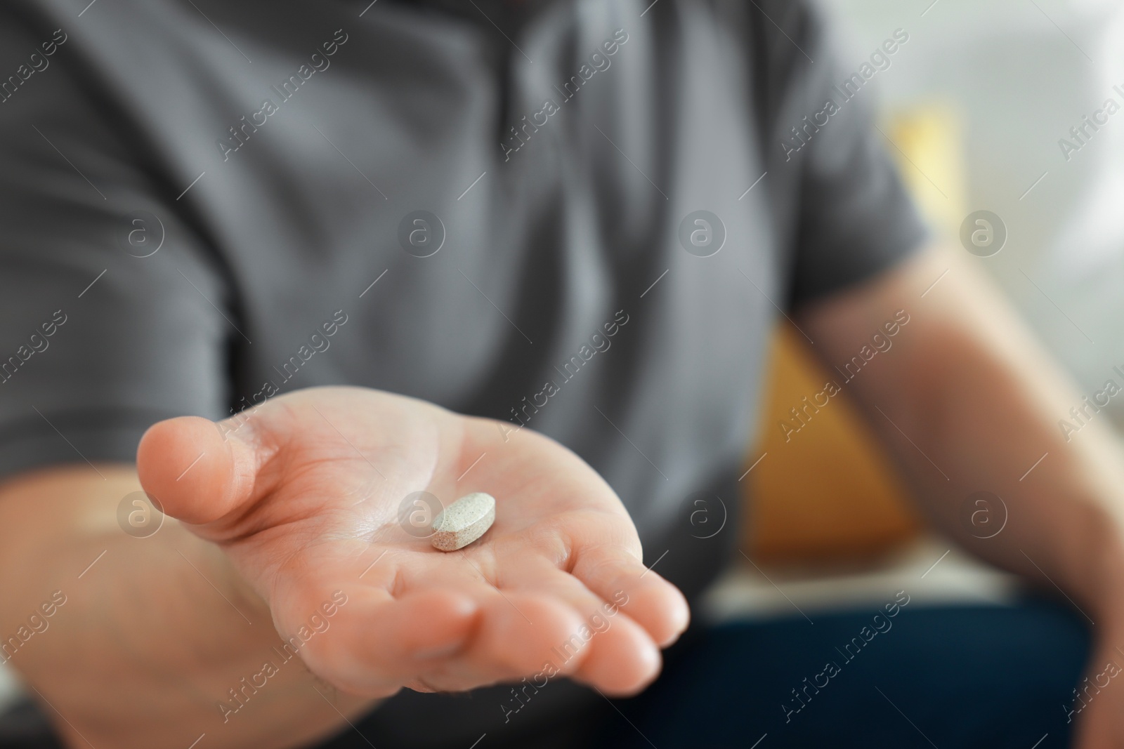 Photo of Man with pill at home, closeup on hand