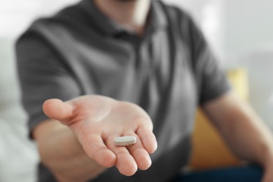 Photo of Man with pill at home, closeup on hand