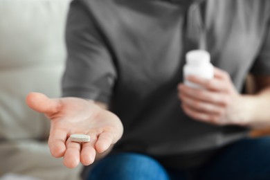 Photo of Man with pill at home, closeup on hand