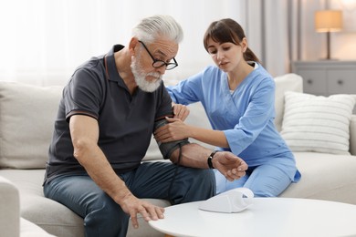 Nurse measuring senior man's blood pressure at home