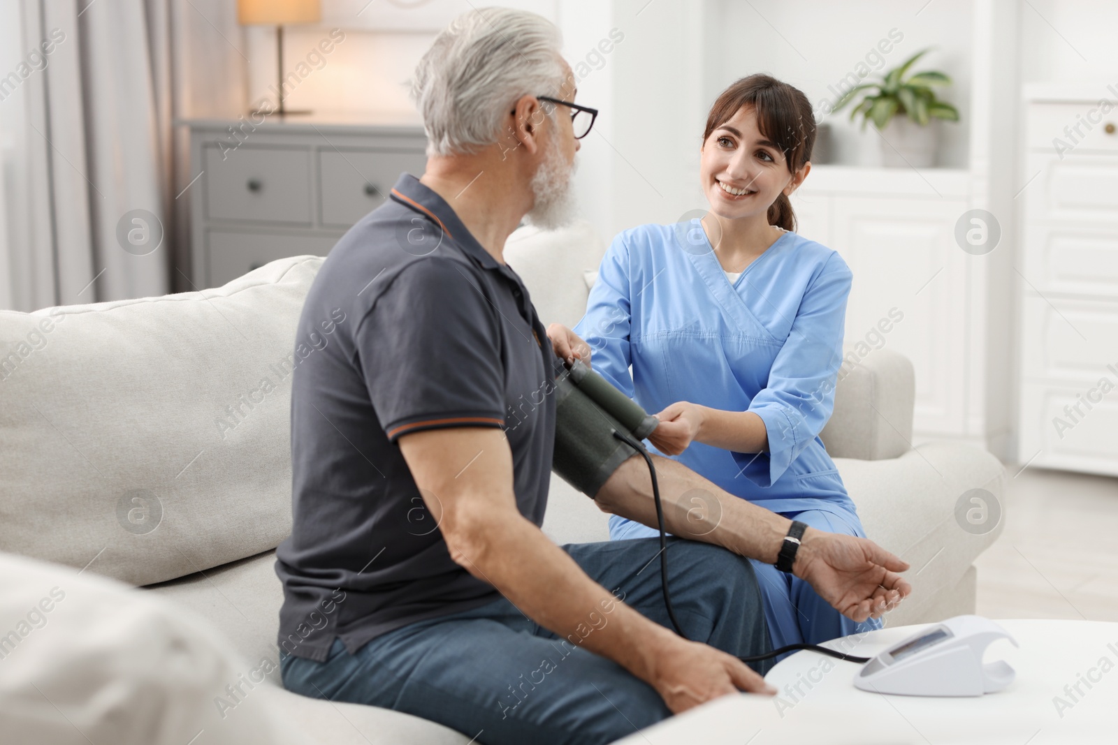 Photo of Nurse measuring senior man's blood pressure at home