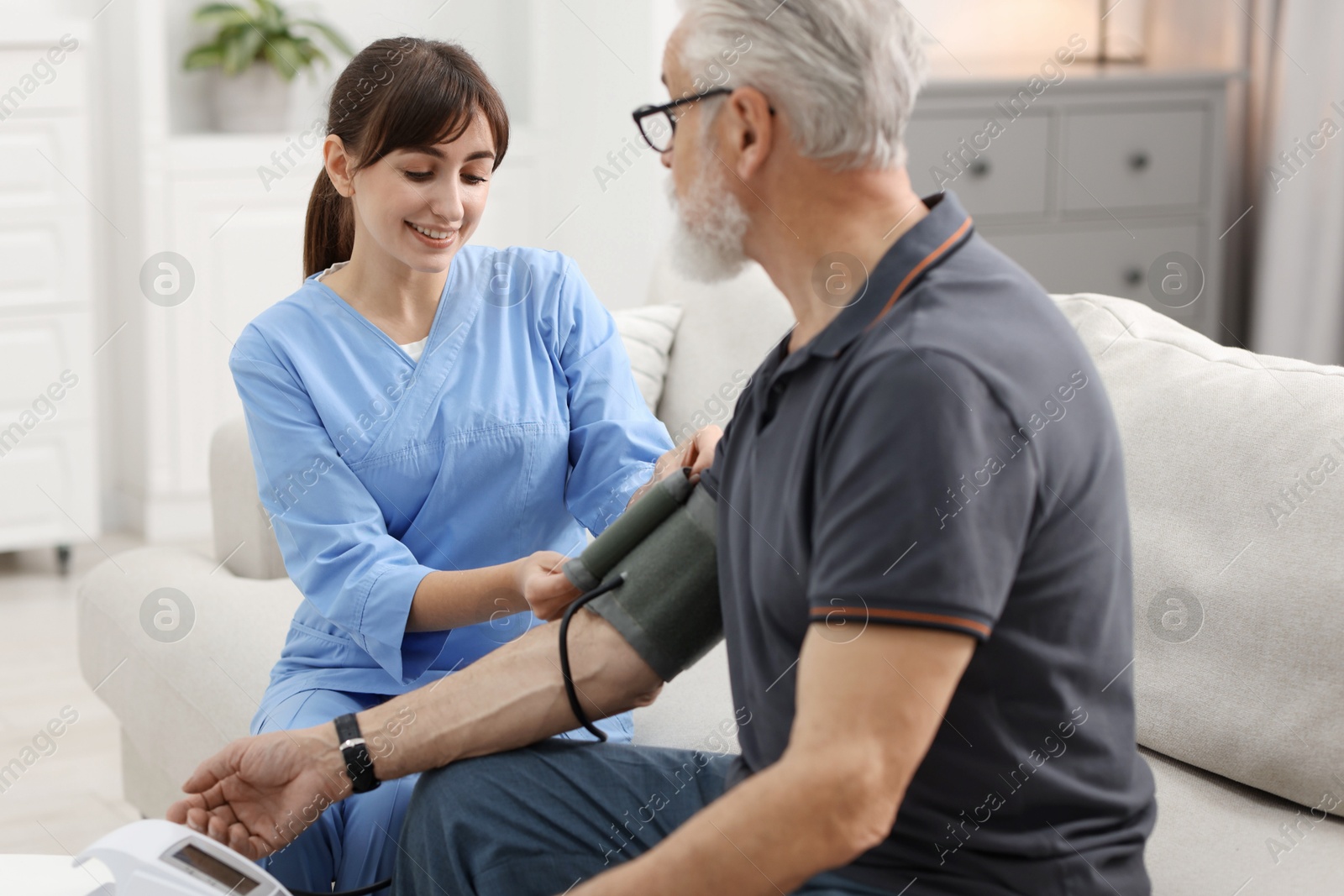 Photo of Nurse measuring senior man's blood pressure at home