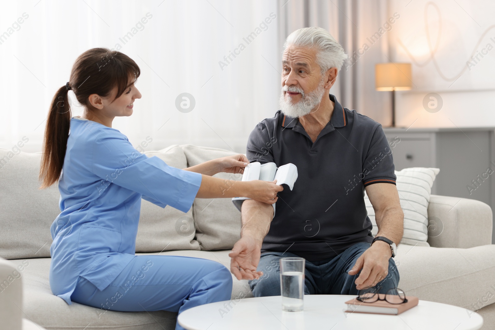 Photo of Nurse measuring senior man's blood pressure at home