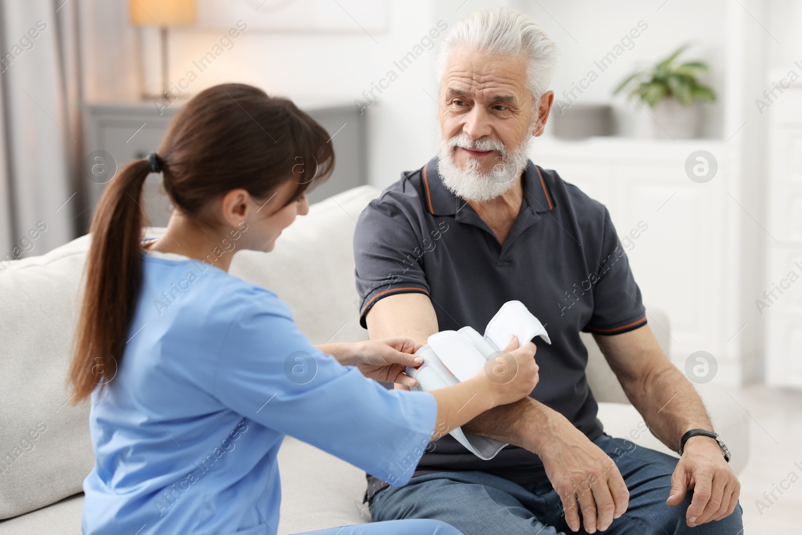 Photo of Nurse measuring senior man's blood pressure at home