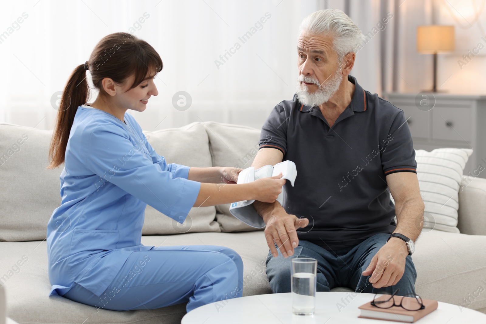 Photo of Nurse measuring senior man's blood pressure at home