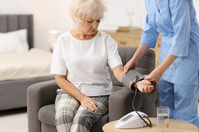 Photo of Nurse measuring senior woman's blood pressure at home