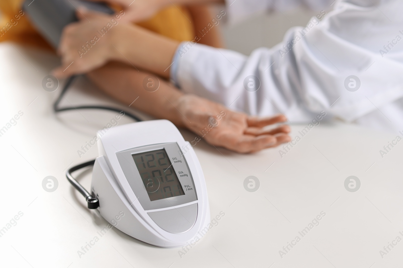 Photo of Doctor measuring senior woman's blood pressure at table, closeup