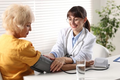 Photo of Doctor measuring senior woman's blood pressure during appointment in hospital