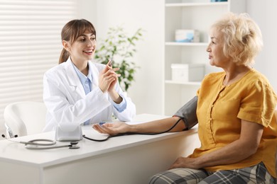 Photo of Doctor measuring senior woman's blood pressure during appointment in hospital