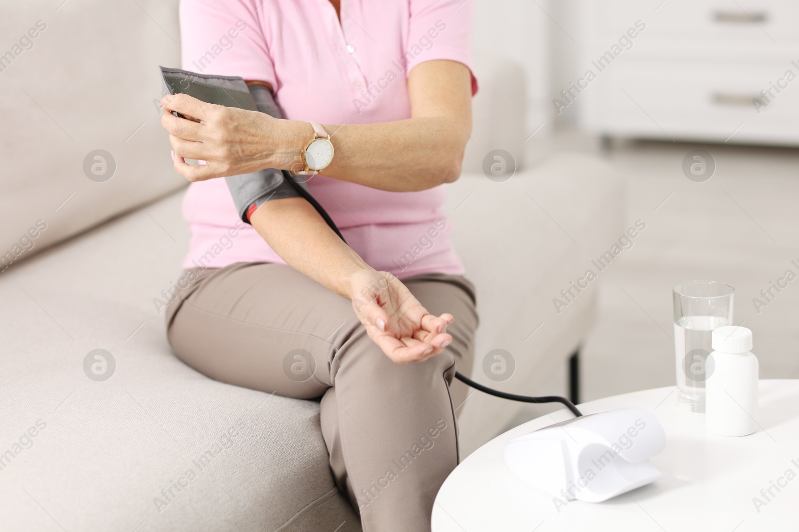 Photo of Senior woman measuring blood pressure on sofa at home, closeup