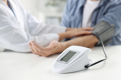 Photo of Doctor measuring senior man's blood pressure during appointment in hospital, closeup