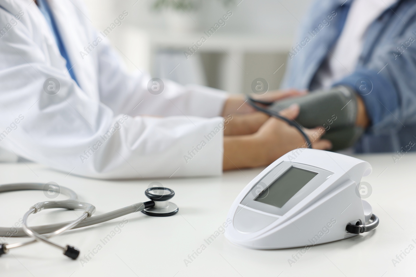 Photo of Doctor measuring senior man's blood pressure during appointment in hospital, closeup. Selective focus