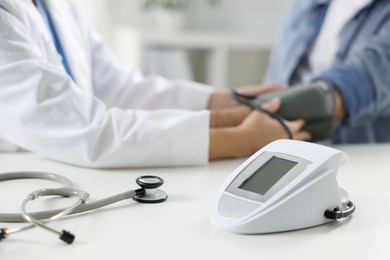 Photo of Doctor measuring senior man's blood pressure during appointment in hospital, closeup. Selective focus