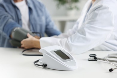 Photo of Doctor measuring senior man's blood pressure during appointment in hospital, closeup. Selective focus