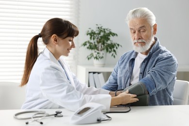 Doctor measuring senior man's blood pressure during appointment in hospital